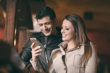 Fashionable couple spending time together, she is holding a mobile touch screen phoneの写真素材