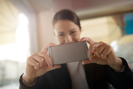 Cheerful woman taking a picture with her touch screen smartphone