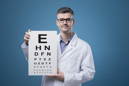 Professional optician holding an eye exam chart with lettersの写真素材