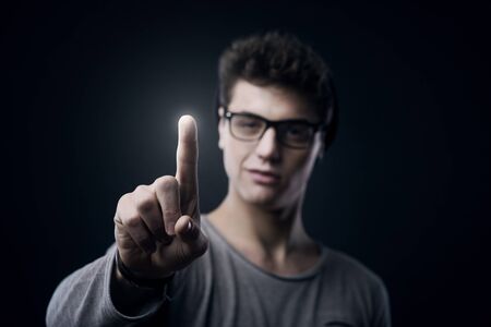 Smiling teenager using touch screen interface with index fingerの写真素材