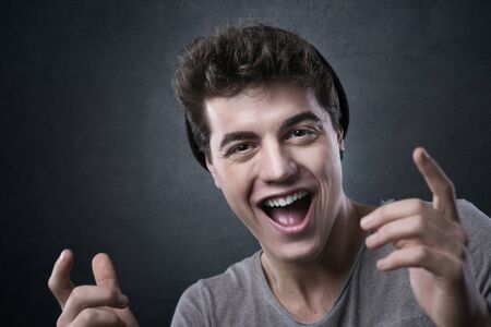 Excited cheerful young man smiling at camera with hands raised