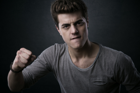 Young aggressive man showing fists and looking at cameraの写真素材