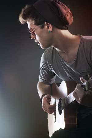 Attractive teenager rock star on stage playing acoustic guitarの写真素材