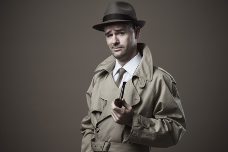 Funny vintage investigator in trench coat holding a pipeの写真素材