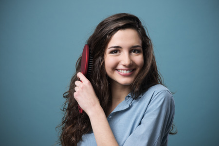 Happy woman brushing her beautiful healthy wavy hair