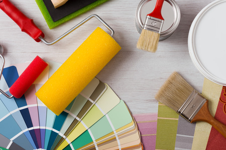 Painter and decorator work table with house project, color swatches, painting roller and paint...