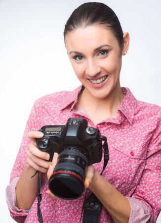 Smiling female photographer on white checking camera previewsの写真素材