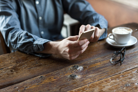 Young man at the bar having a coffee break and using a mobile touch screen phoneの写真素材