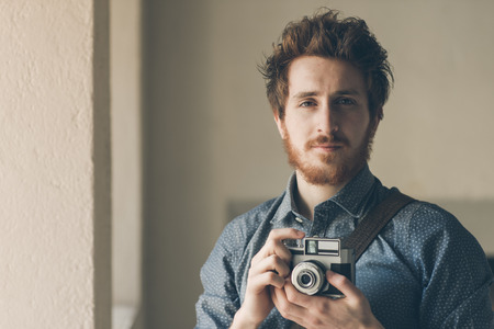 Vintage photographer portrait, he is holding an old camera and posingの写真素材