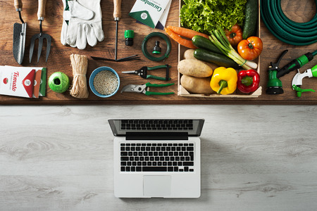 Gardening and farming tools on a wooden table and laptop, top viewの写真素材