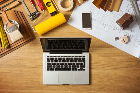 Do it yourself home remodeling and renovation concept, work table top view with tools, project, laptop, house model and keysの写真素材