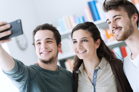 Smiling happy teenagers taking selfies with a mobile phone, sharing, technology and friendship...