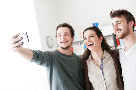 Smiling happy teenagers taking selfies with a mobile phone, sharing, technology and friendship...