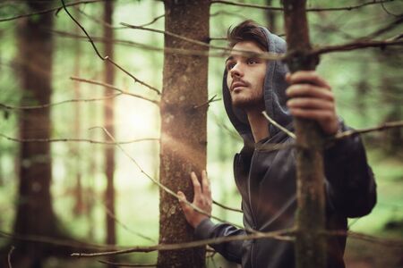 Hooded guy in the woods exploring nature, individuality and freedom conceptの写真素材