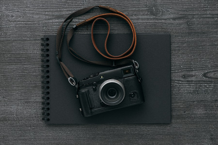 Empty black photo album and professional digital camera on a dark desktopの写真素材