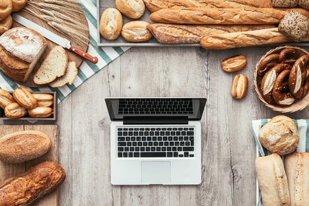 Tasty healthy fresh bread surrounding a laptop, technology and healthy eating concept, flat layの写真素材