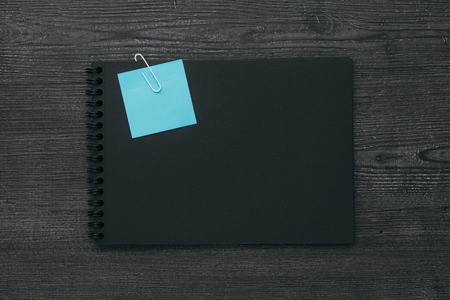 Blank dark notebook with blue memo note, planning and reminders conceptの写真素材