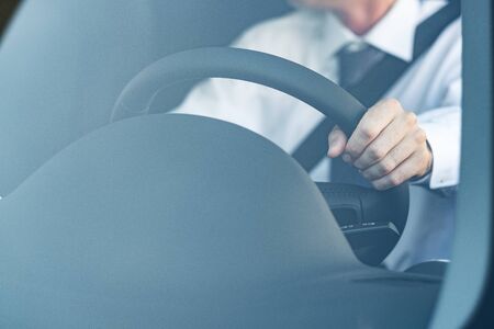Man sitting in a car and driving, hand on the steering wheel close upの写真素材