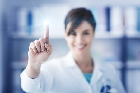 Female doctor using a touch screen interface, she is pointing with her index finger, healthcare and...