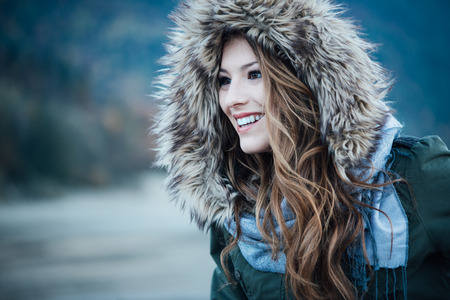 Young smiling woman with fur hood, fashion and winter concept