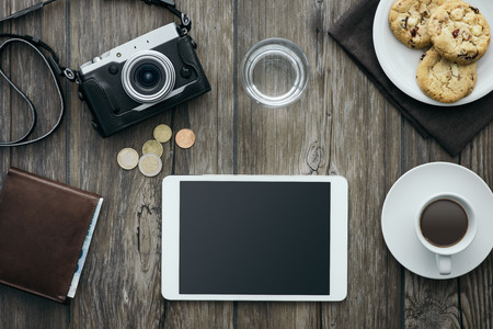 Vintage camera, tablet, a cup of coffee and cookies on a wooden desktop, relaxing breakfast at home conceptの写真素材