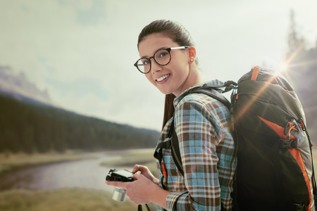 Young smiling photographer woman trekking in nature on the mountains and shooting with her digital cameraの写真素材