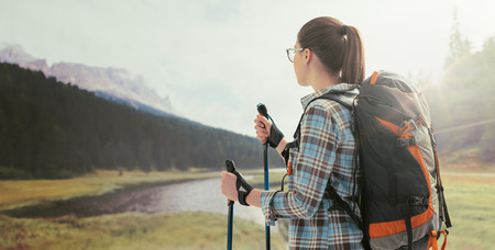 Young female hiker trekking on the mountains and contemplating the panorama, she is using trekking polesの写真素材