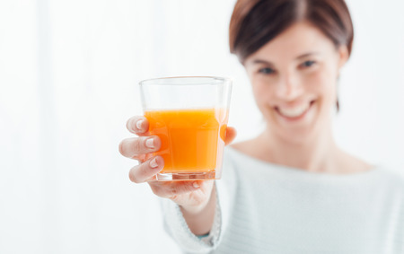 Smiling woman holding a glass of fresh orange juice, healthy diet conceptの写真素材