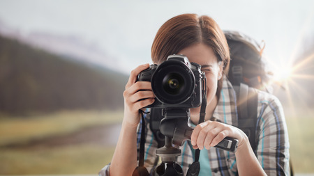 Photographer trekking in nature and shooting with a professional digital camera and a tripodの写真素材