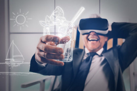 Businessman wearing a VR headset and enjoying a virtual vacation, he is relaxing on a deckchair and holding a virtual drinkの写真素材