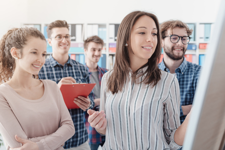 Young business team discussing together a project on a whiteboard: startups, communication and new business conceptの写真素材