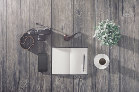 Hipster vintage wooden desktop with camera, smartphone and blank open notebook, top viewの写真素材