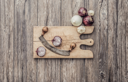 Onions and garlic on the kitchen worktop with rustic chopping board, healthy eating and cooking conceptの写真素材