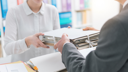 Boss handing paperwork to his young female employee
