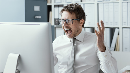 Cheerful businessman working with his computer and celebrating his success, he is receiving surprising good newsの写真素材