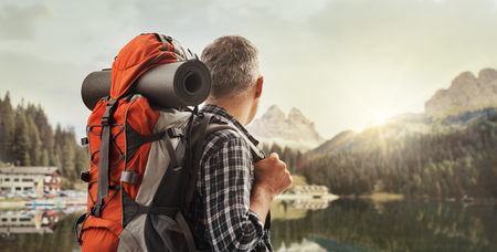 Hiker trekking on the mountains and contemplating the panorama, he is carrying a backpack and hiking equipment, sports and nature conceptの写真素材