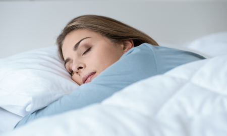 Young beautiful woman sleeping in the bed, she is relaxing and dreaming with eyes closed, healthy lifestyle conceptの写真素材