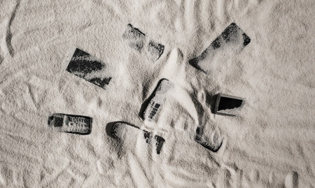 Phones and touch screen devices under the sand on the beachの写真素材