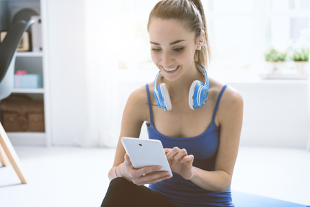 Happy sporty woman with headphones, she is searching music online using her digital tabletの写真素材