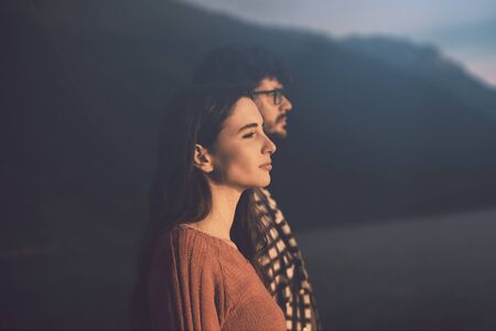 Young couple standing together and looking at the sunset outdoors