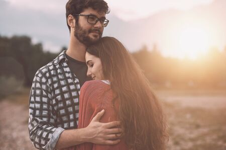 Young loving couple hugging each other outdoors, trees and nature in the background