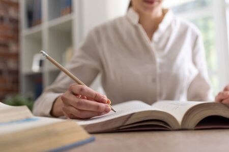 College student studying, she is writing notes on a book, hand close upの写真素材