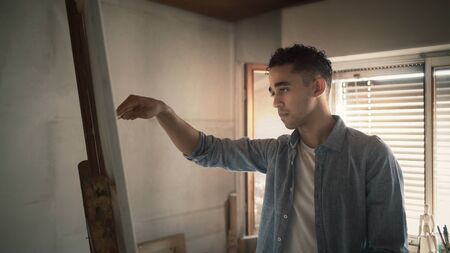 Young creative artist in his workshop, he is painting on canvas, art and inspiration conceptの写真素材