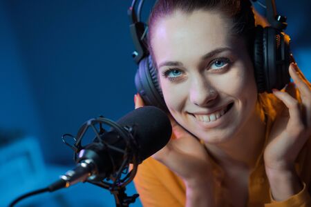 Young charming host working in the radio station, she is smiling at camera