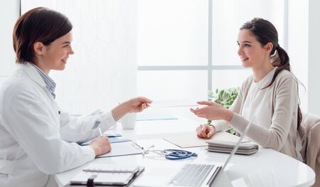 Patient in the doctor's office, she is smiling and receiving a prescription, healthcare and treatment conceptの写真素材