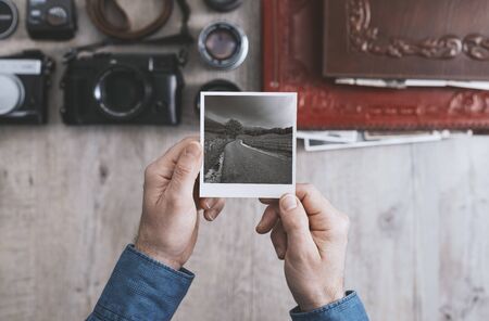 Photographic equipment, cameras and photo albums on a vintage desktop, a photographer is holding a...