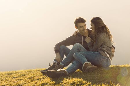Happy young couple sitting on grass during a sunny day and enjoying time together, love and relationships conceptの写真素材