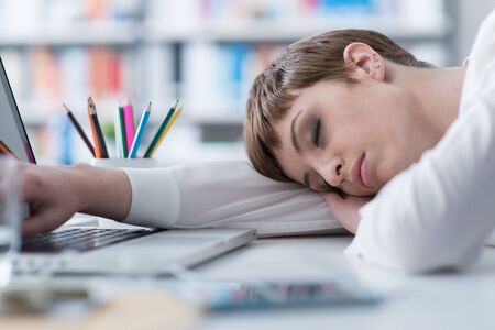 Tired businesswoman sleeping on her desk and leaning on her armの写真素材
