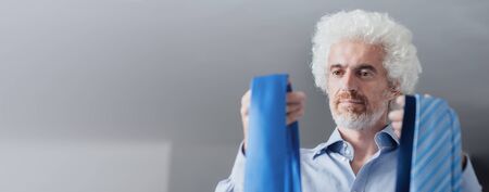 Businessman holding a lot of neckties, outfit color matching and male fashion conceptの写真素材