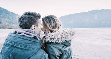 Teenagers kissing and flirting, lake and mountains on background, first crush and romance conceptの写真素材